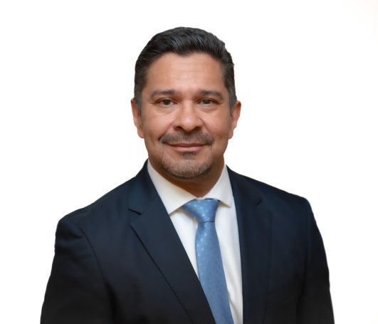 Headshot of executive in a suit with a light blue tie, standing against a white background in studio at Miami Headshot Studio Portrait.